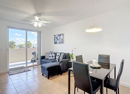 A living room with a sliding glass door and a dining table with chairs.
