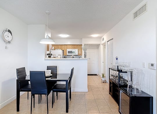 A black dining table with four chairs is in a dining room with white walls.