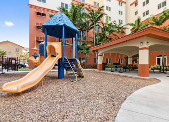 A playground with a yellow slide and a blue roofed structure.