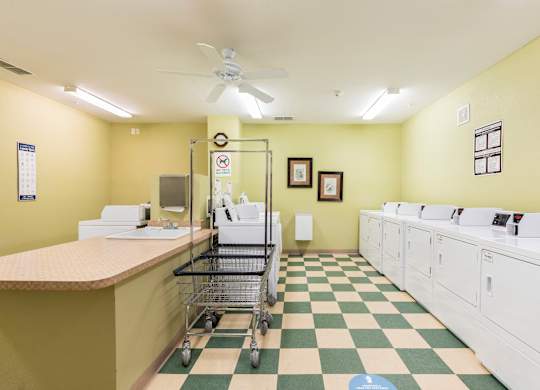 A laundry room with a checkered floor and a row of washers and dryers.