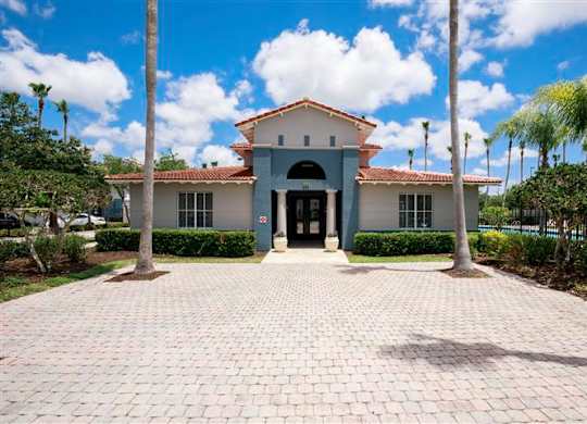 A building with a red tile roof and a brick walkway in front.