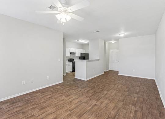 A room with a ceiling fan and wooden flooring.