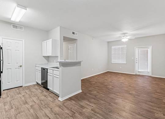 A kitchen with white cabinets and a wooden floor.