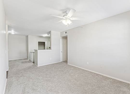 A spacious room with a ceiling fan and carpeted floor.