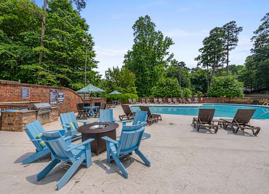A poolside area with blue chairs and a fire pit.