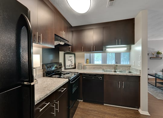 A kitchen with dark brown cabinets and black appliances.