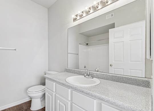 A white bathroom with a toilet, sink, and mirror.