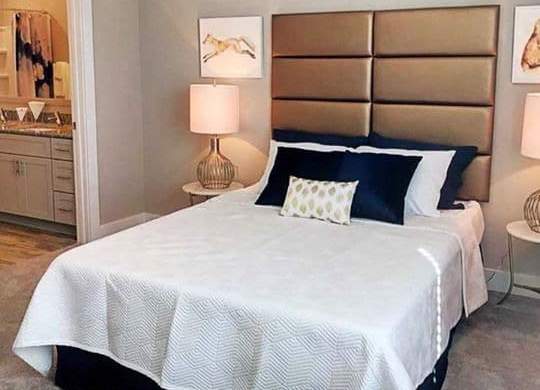 A bed with a white comforter and a blue pillow is in the image at Foxwood Apartments, North Carolina, 27616