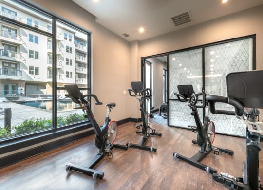 Gym area with multiple cardio bikes and a window with view of the pool