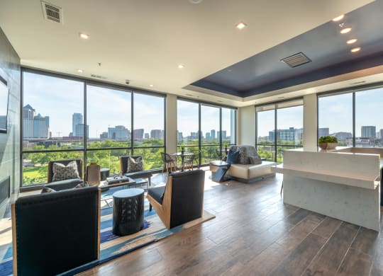 Resident common area with floor-to-ceiling windows and a view of Dallas skyline with multiple chairs and tables and a white marble island