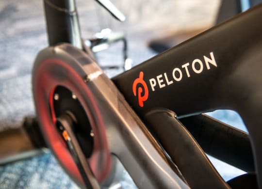 Close up of the peloton logo on the leg of a black bike machine