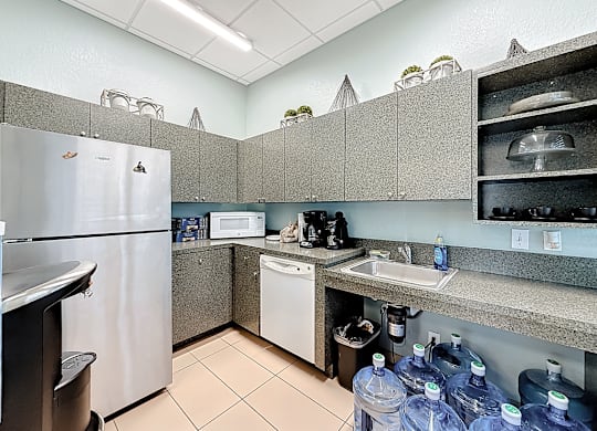 A kitchen with a stainless steel refrigerator, a white dishwasher, and a sink.