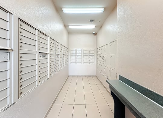 A long hallway with a row of mailboxes on the left and a row of lockers on the right.