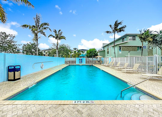 A swimming pool with a blue tiled wall and a diving board.