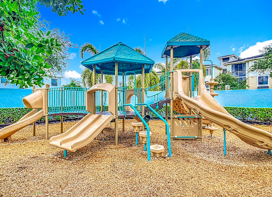 A playground with a blue slide and a green roofed structure.