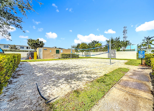 A sunny day at a park with a blue signboard and a yellow building.