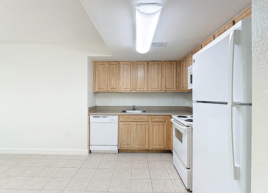 A kitchen with white appliances and wooden cabinets.