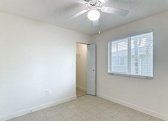 A room with a ceiling fan and a door leading to another room.