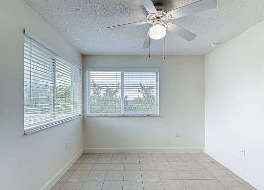 A room with a ceiling fan and a window with blinds.