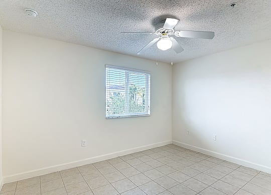 A room with a ceiling fan and a window with blinds.