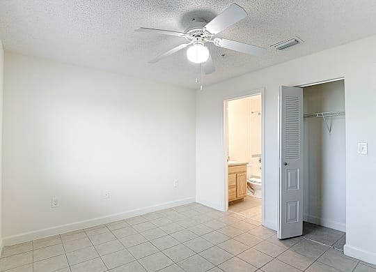 A room with a ceiling fan and tile flooring.