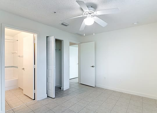 A white room with a ceiling fan and tile flooring.