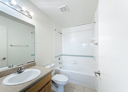 A white toilet is in a bathroom with a sink and a bathtub.