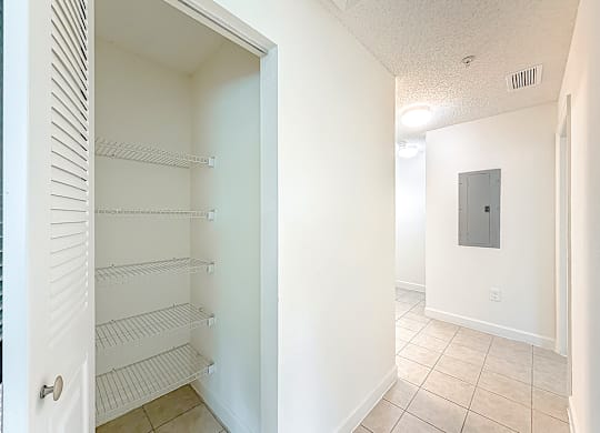 A white pantry with a door open to a hallway.