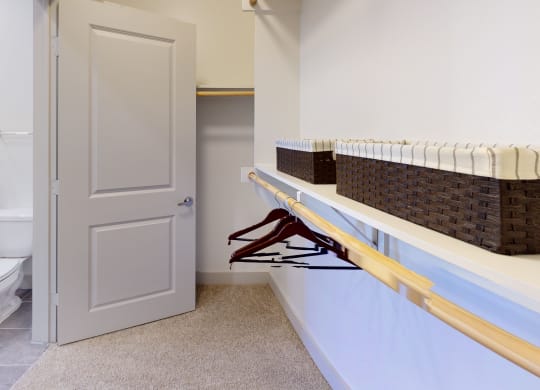Large walk-in closet facing a long shelf and interior of the bathroom