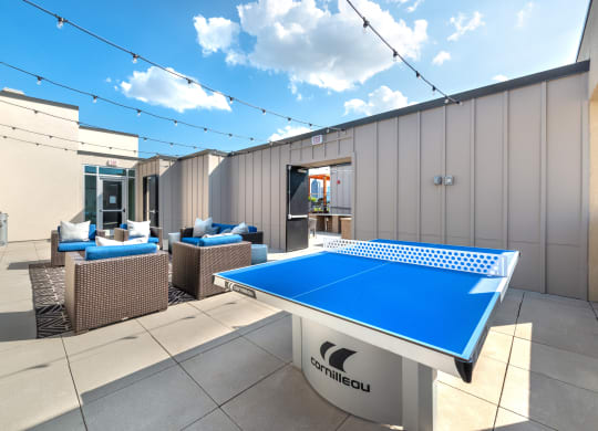 Outdoor sitting area next to a ping pong table and grilling area