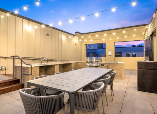Outdoor grilling area with a long table, sink, and grill facing downtown Dallas