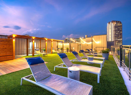 Lounge chairs sitting next to the rooftop pool that faces downtown Dallas