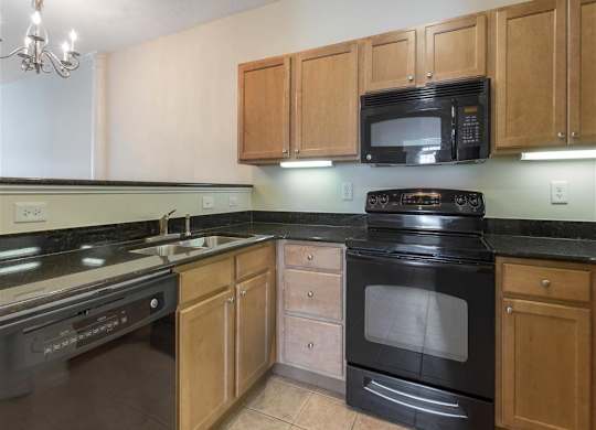 Kitchen with Brown Cabinets Black Appliances and Black Counters and Breakfast Bar