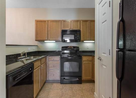 Kitchen with Brown Cabinets Black Appliances and Black Counters Pantry Closet and Breakfast Bar