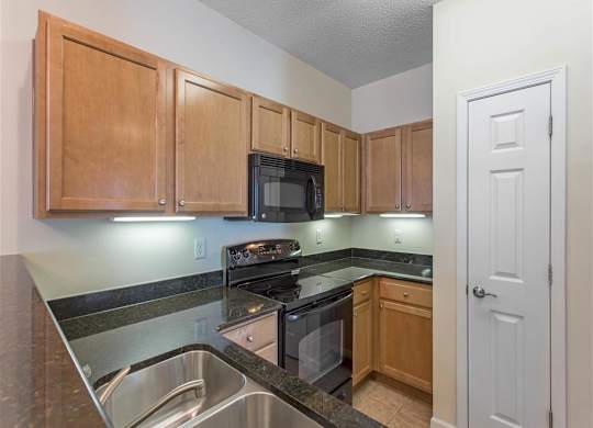 Kitchen with Brown Cabinets Black Appliances and Black Counters Pantry Closet and Breakfast Bar