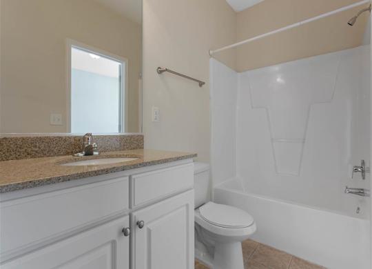 Bathroom with Bathtub and Shower Tan Counters White Cabinets and Linen Closet Door