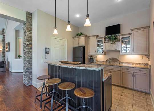 Clubhouse Kitchen with Tan Counters Black Appliances and Wood and Metal Stools at Breakfast Bar