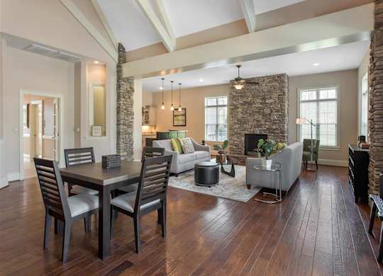 Clubhouse Seating Area with Dining Room Table with Chairs  Grey Couches Triangle Glass Coffee Table Brick Fireplace with Windows and Decorations