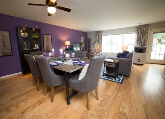Dining room with large dining table with ceiling fan and living room in the background.