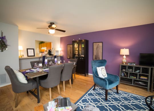 Dining room table with ceiling fan above the table . Living room is next to the dinning room