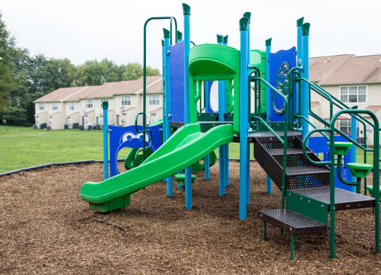 Playground with wood chips in court yard between buildings.