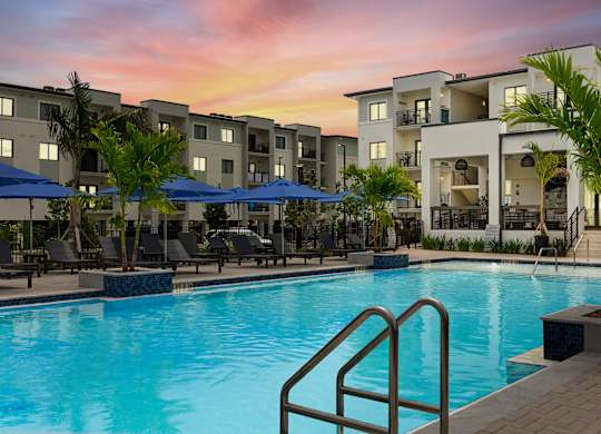 a swimming pool at sunset at an apartment complex