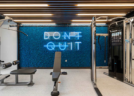 a gym with a blue neon sign on the wall and a gym chair