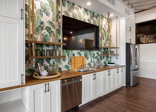 a kitchen with white cabinets and a sink and a television