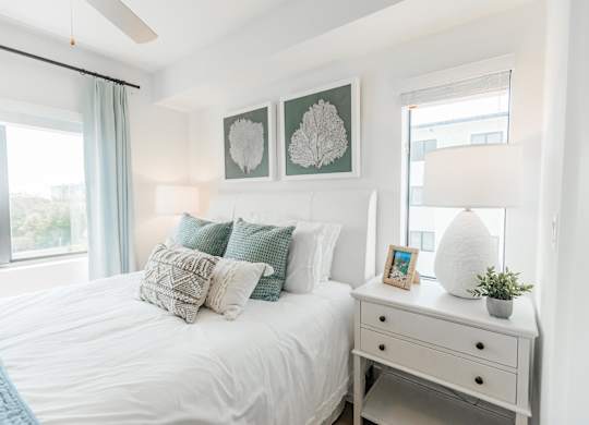 a bedroom with a bed with pillows and a dresser with a lamp and