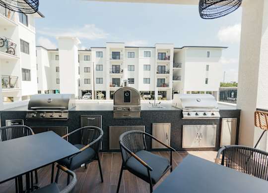 a patio with a grill and tables with chairs