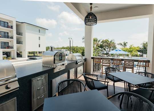 a covered patio with tables and chairs and barbecue grills