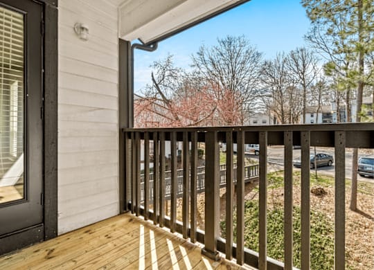 A balcony with a black railing and a view of trees and cars at Paces Pointe Apartment Homes, Matthews