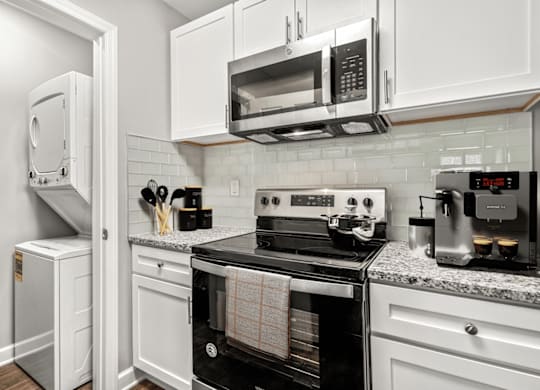 A kitchen with white cabinets and black appliances at Paces Pointe Apartment Homes, North Carolina