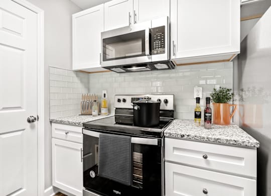 A kitchen with a black stove top oven and white cabinets at Paces Pointe Apartment Homes, Matthews